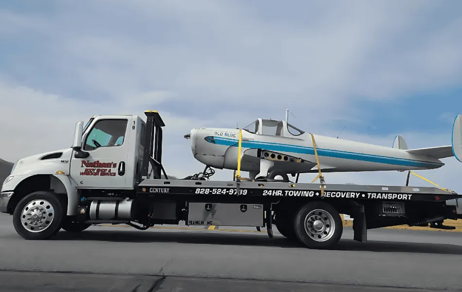 Airplane towing on a flatbed tow truck for safe transport.