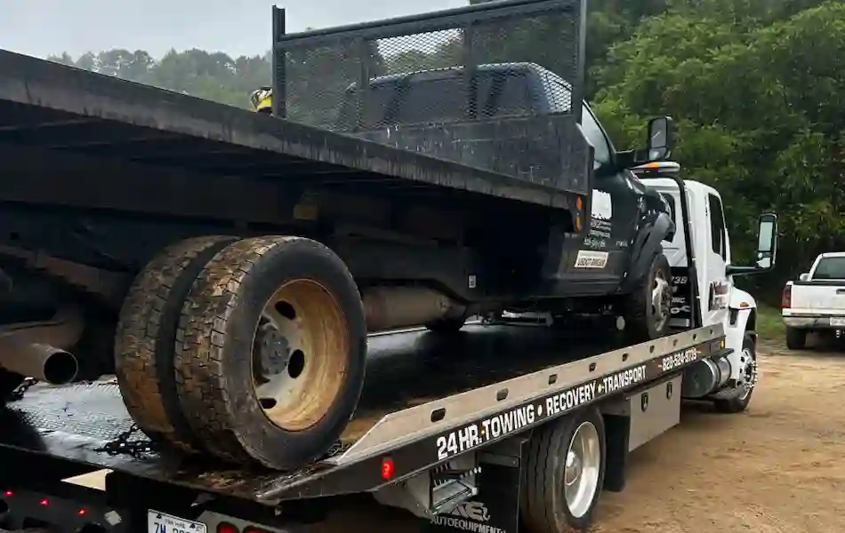 Dually truck being towed on a rollback by Nathan’s Body Shop & Wrecker Service in Franklin NC.