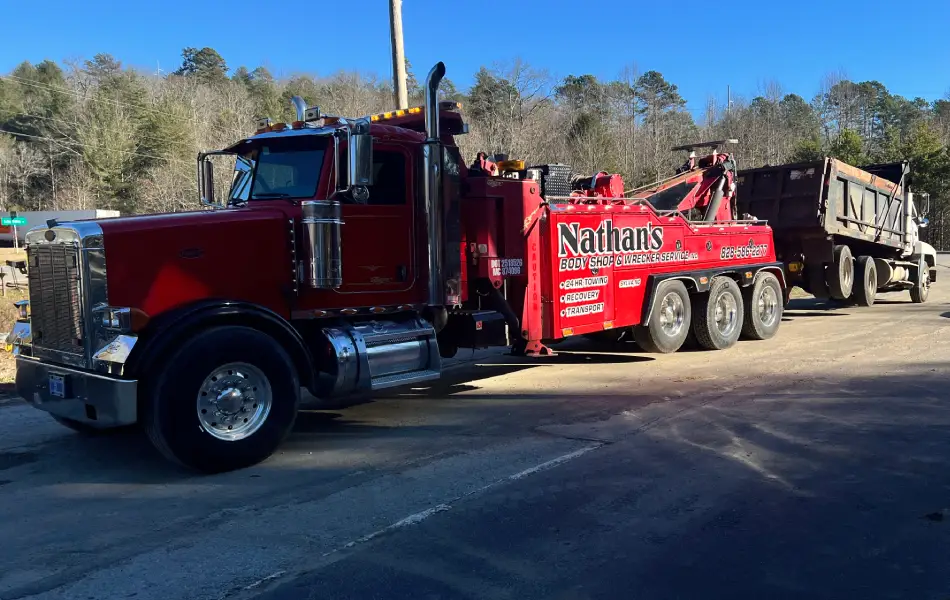 Heavy-duty towing with a red Peterbilt wrecker hauling a large truck.