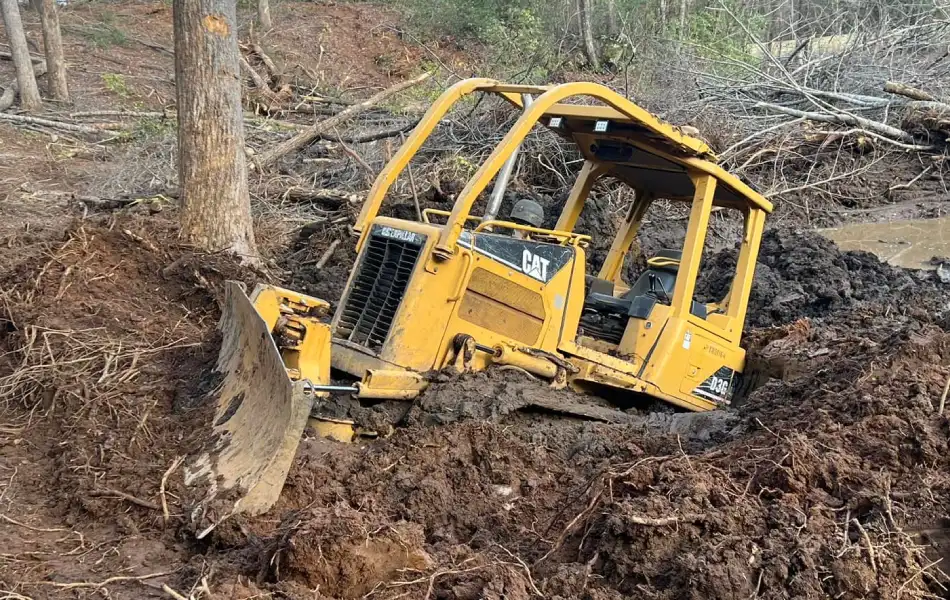 Heavy duty towing team recovering a stuck CAT dozer from deep mud in Western North Carolina